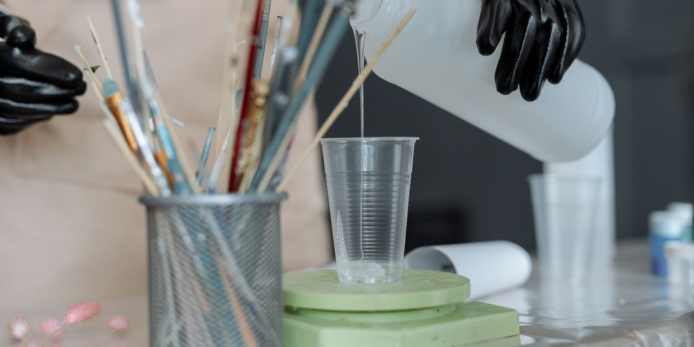 Resin poured into a cup among art tools and gloves