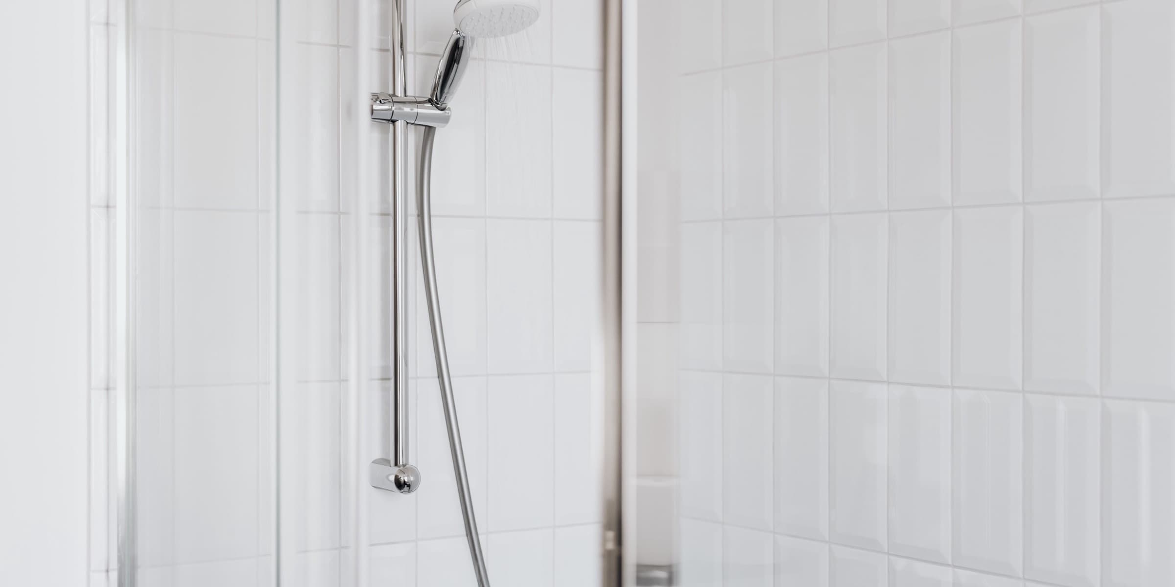 Shower with chrome fixtures and white tiles