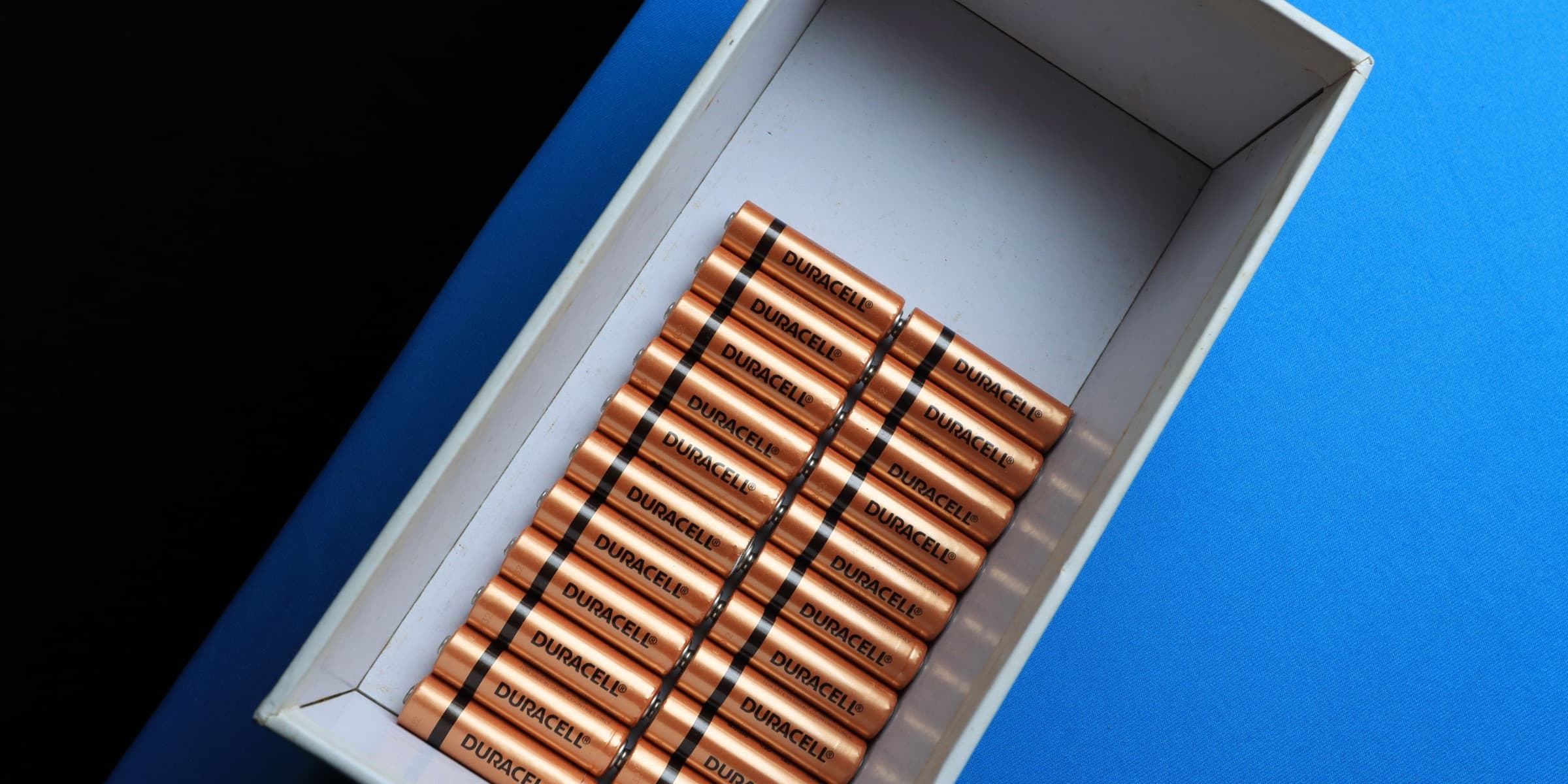 Batteries arranged in a box on a blue surface